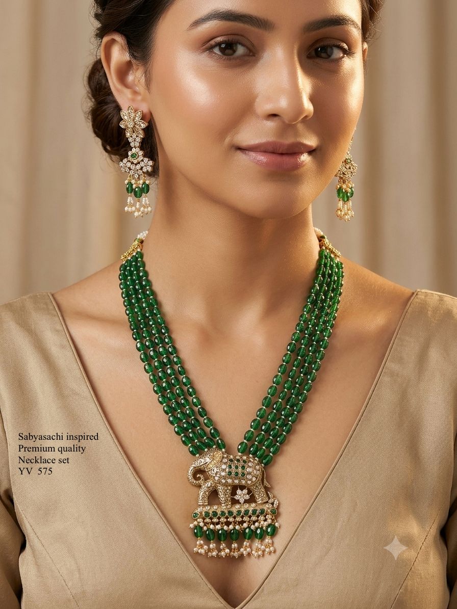 Close-up of model wearing a Sabyasachi-inspired gold-plated 4-strand emerald green bead necklace set featuring an encrusted royal elephant pendant and matching drop earrings
